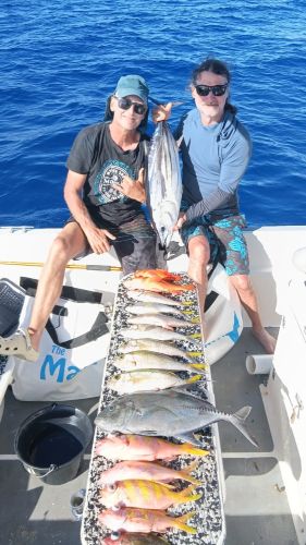 Anglers with various fish caught on the reef, lined up on the boat deck